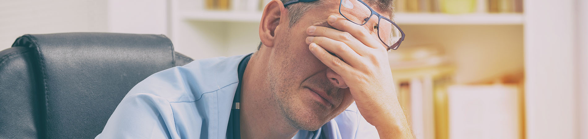 A provider showing signs of physician burnout with visible signs of exasperation