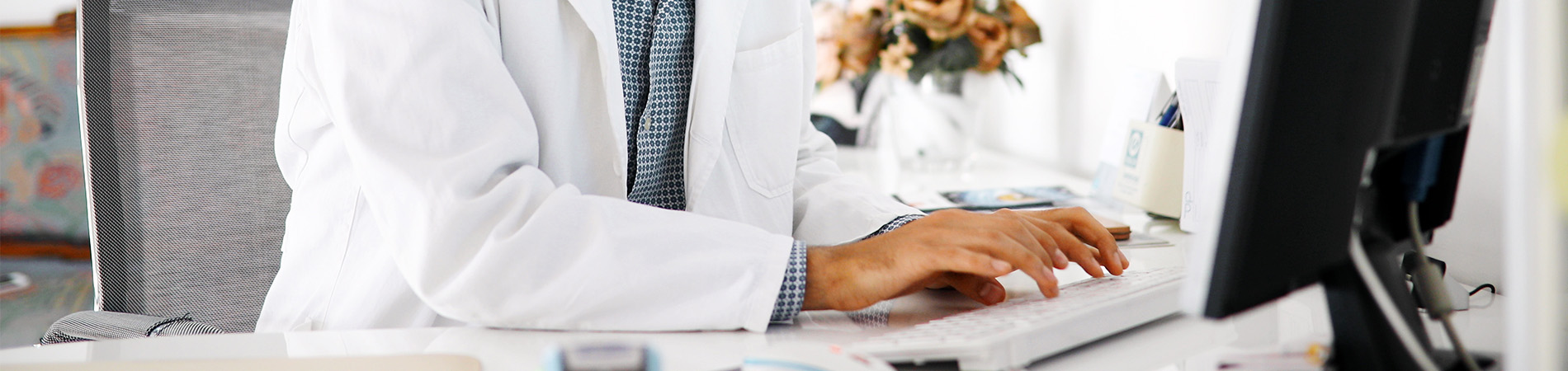 Happy male doctor staring at a computer screen avoiding HIPAA violations