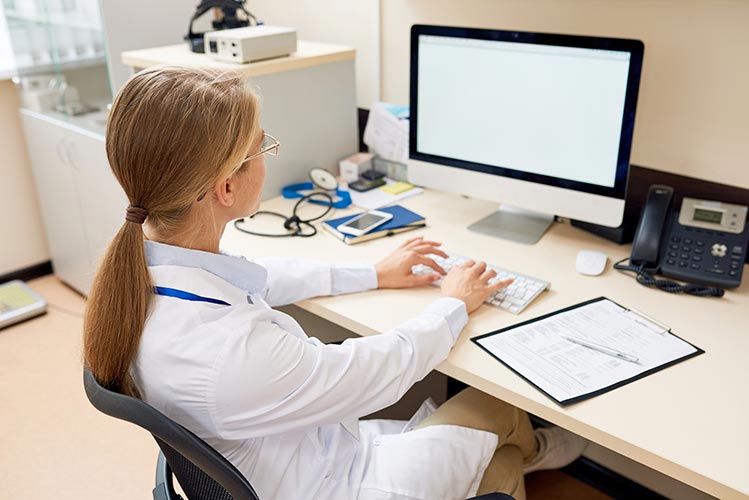 Female doctor inputting information at computer terminal
