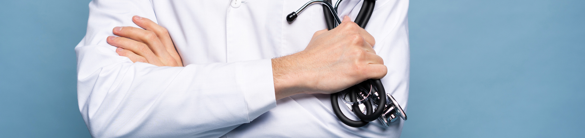 confident doctor stands with arms crossed holding a stethoscope